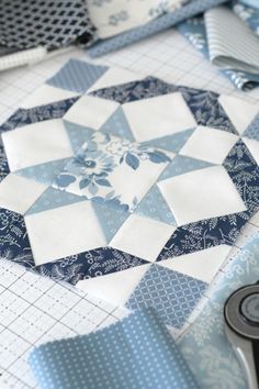 blue and white quilts laid out on top of each other with sewing tools next to them