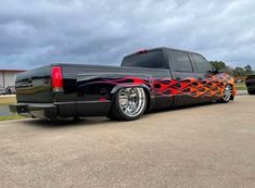 a black truck with red flames painted on it's tailpipes parked in a parking lot