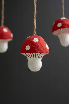 three red and white mushrooms hanging from strings