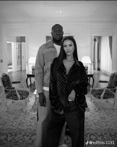 a man and woman standing next to each other in front of a living room filled with furniture