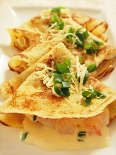 three quesadillas on a white plate topped with cheese and green onions