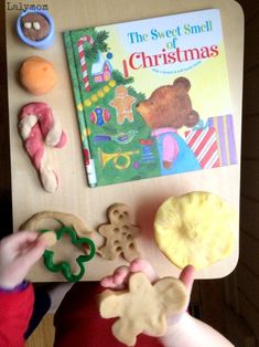 a child is holding cookies in front of a book about the sweet smell of christmas