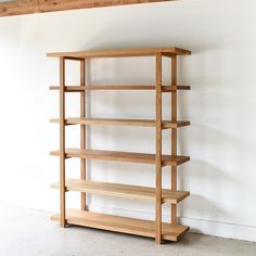 a wooden book shelf sitting in the corner of a room with no one on it