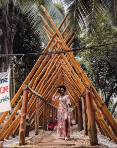 a woman standing in front of a wooden structure made out of sticks and bamboo poles