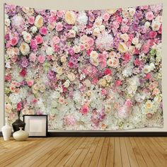 a large floral wall hanging on the side of a wooden floor next to vases