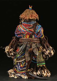 a sculpture made out of different types of beads and leathers, with an elaborate headdress