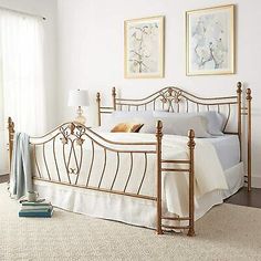 a white bed sitting in a bedroom next to two pictures on the wall above it