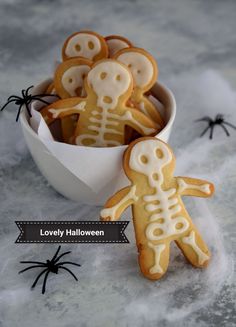 several decorated cookies in a bowl with spider webs on the table next to them