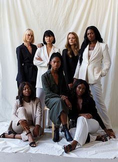 a group of women sitting next to each other in front of a white backdrop, posing for the camera