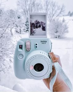 a person holding up a polaroid camera in the snow