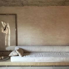 a white couch sitting in front of a window next to a wall with a clock on it