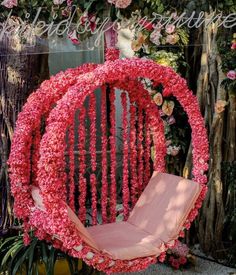 a pink chair sitting in front of a flower covered wall with flowers on it's back