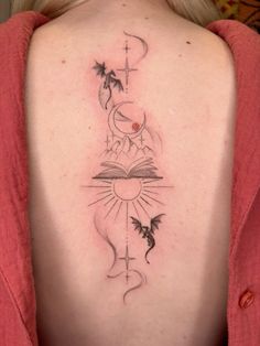 the back of a woman's shoulder with a tattoo on her upper arm and an open book