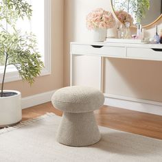 a white table with a mirror, potted plant and stool in front of it