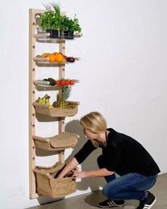 a woman kneeling down next to a wooden shelf