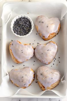 four donuts with white icing and sprinkles in a tray on a table