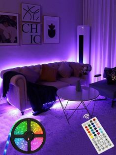 the living room is lit up with purple lighting and remote controls on the table next to the couch