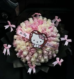 a hello kitty bouquet with pink and white roses in the center is surrounded by bows