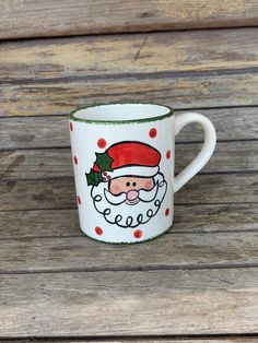 a coffee mug with a santa clause on it sitting on top of a wooden table