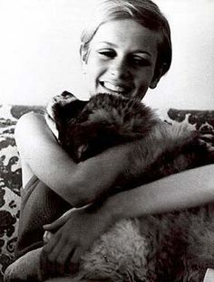 a woman sitting on a couch holding a cat in her arms and smiling at the camera