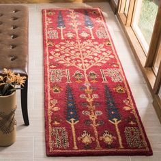 a red runner rug on the floor next to a bench and vase with flowers in it