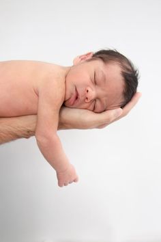 a man holding a sleeping baby in his arms on a white background for a newborn photo