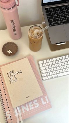 a laptop computer sitting on top of a desk next to a cup of coffee and a notebook