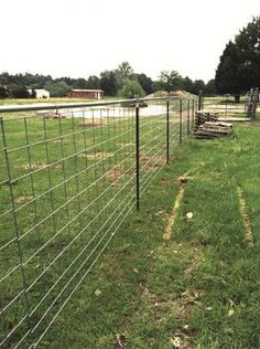 a fence that is in the middle of a field with grass and dirt on it