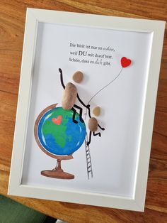 a framed artwork depicting a person holding a balloon and climbing a ladder to the top of a globe