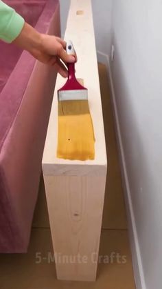 a person using a brush to paint a piece of furniture with yellow and red colors