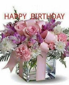 a vase filled with pink and white flowers sitting on top of a table next to a happy birthday sign