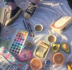 an assortment of food and other items on a sheet with watercolors, pencils, paintbrushes