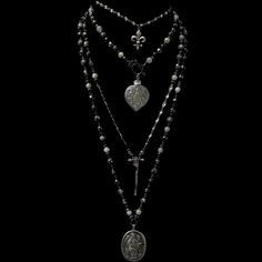 The Lujan Choker features an intricately carved Our Lady of Lujan medal within a flaming Sacred Heart made of Sterling Silver. She's surrounded by Angels, with two of them raising a crown of flowers above her. Pilgrims worldwide travel to see Her and have received special graces, favors and miracles. The gunmetal linked chain is offered in 17" or 22" based on your preference. If you need a longer or shorter size we can make one for you. It's a very special necklace because of the rarity of the m Silver And Black Necklace, Silver Gothic Jewelry, Trad Goth Jewelry, Ecclesia Jewelry, Long Necklace Outfit, Long Beaded Necklaces, Surrounded By Angels, Goth Jewellery, Crown Of Flowers