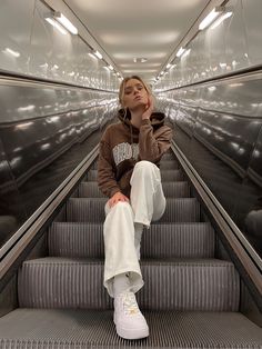 a woman sitting on an escalator with her head in her hands and looking up