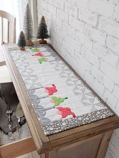 a wooden table with a white brick wall and christmas decorations on the top of it