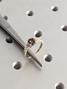 a diamond ring sitting on top of a metal object next to a comb and screwdriver