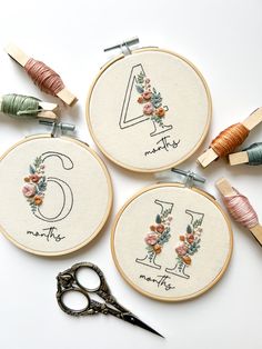 three embroidery hoops with flowers and the number four on them next to some scissors