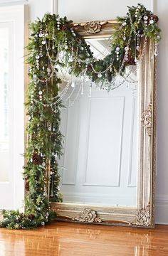 a mirror sitting on top of a wooden floor next to a christmas wreath and garland