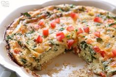 an omelet with tomatoes and spinach in a white casserole dish