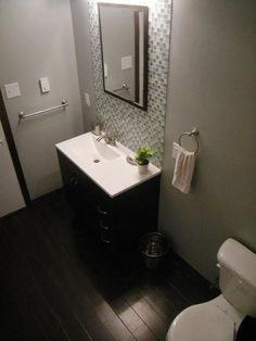 a white toilet sitting next to a sink in a bathroom under a mirror and lights