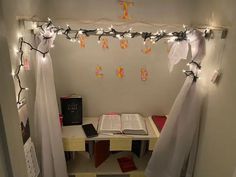 an open book is sitting on a desk with lights strung from the ceiling above it