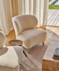 a living room with two chairs and a coffee table in front of a sliding glass door