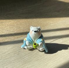 a toy bear sitting on the ground with a tennis ball in it's paws