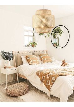 a woman sitting on top of a bed next to a mirror and potted plants