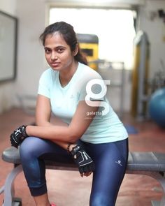 a woman sitting on top of a bench in a gym