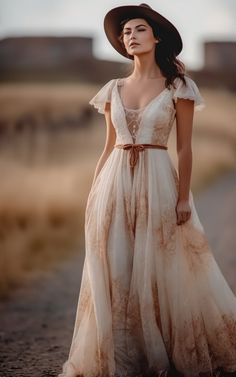 a woman wearing a dress and hat standing in the middle of a dirt road with her hands on her hips