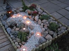 a garden with rocks and lit candles in it