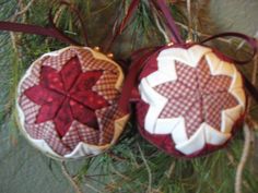 two ornaments hanging from a christmas tree with red and white plaid designs on them, one has an ornament in the shape of a flower