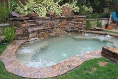 an outdoor hot tub in the middle of a yard with grass and rocks around it