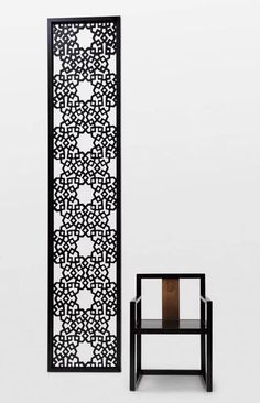 a black and white room divider next to a small table with a vase on it